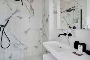 A modern bathroom with a white sink, black fixtures, and marble-patterned walls. - Cosy Cocoon Nestled in Vibrant 11th - Voltaire (Paris)