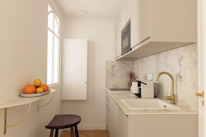 A compact kitchen with a marble countertop, a sink, and a window. - Brand New Flat in Central Marais - Walk Everywhere (Paris)
