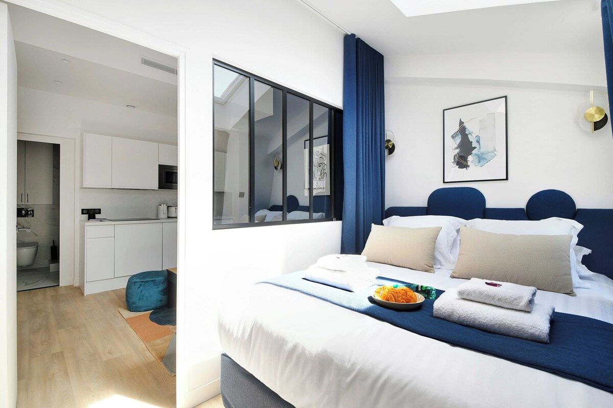 Une chambre d’hôtel moderne dotée d’un grand lit, d’un coin repas et offrant une vue sur la ville.