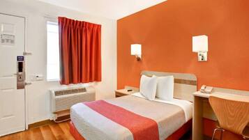 A hotel room with a bed, bedside tables, a telephone, an air conditioning unit, and a window with curtains.