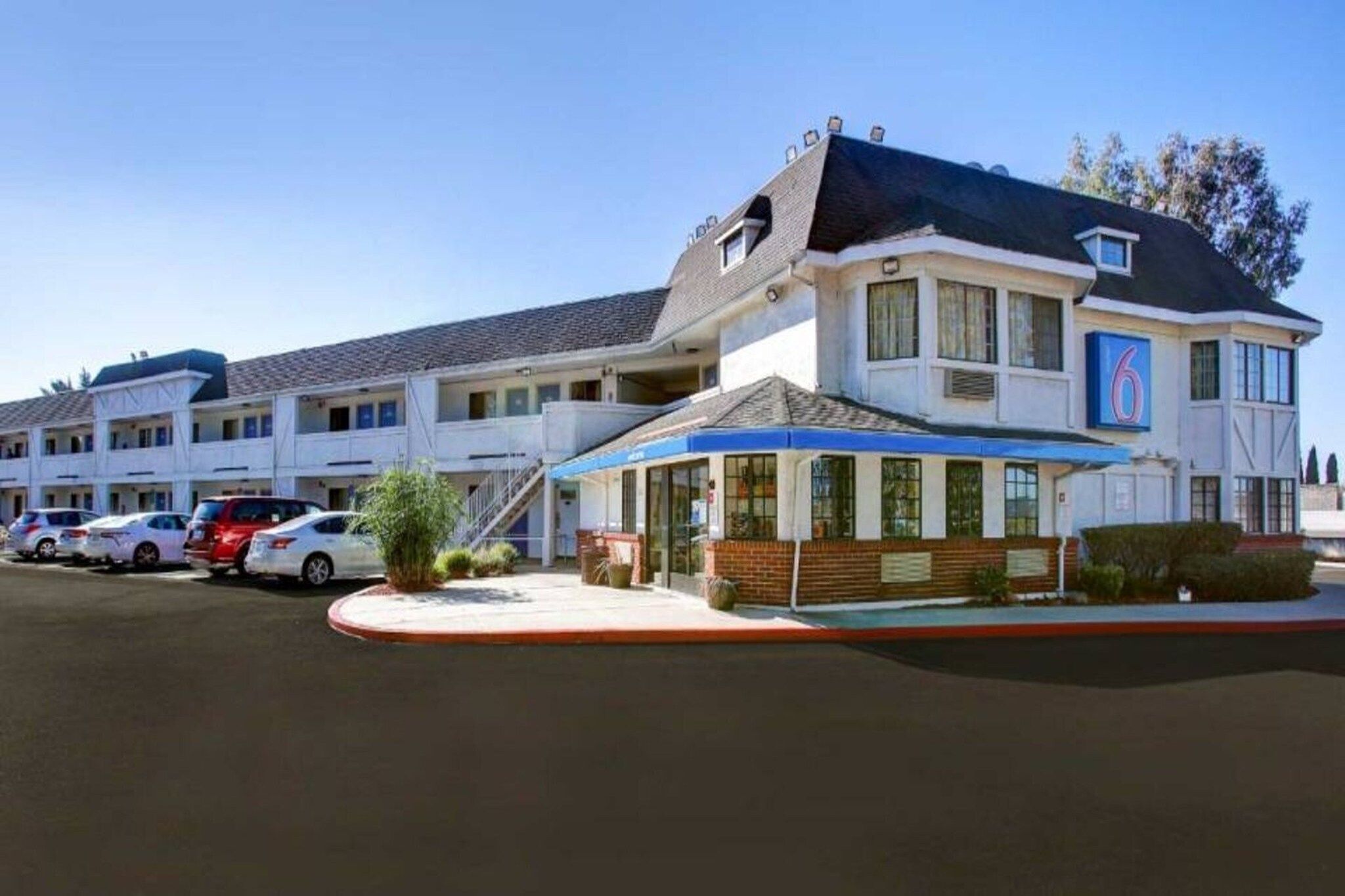 A motel with a central building and a smaller attached structure, both featuring a flat roof and a single-story design.