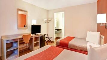 A hotel room with two beds, a desk, a chair, a television, and a mirror.