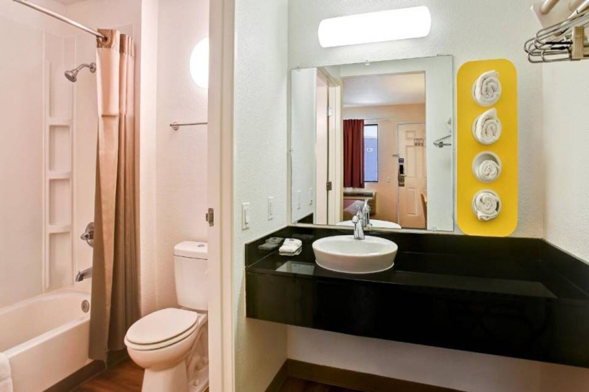 A bathroom with a bathtub, toilet, and a sink with a mirror above it.