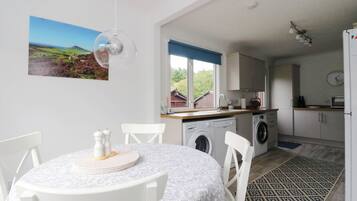 A modern kitchen with a washing machine, a sink, and a window with a view of the outdoors.