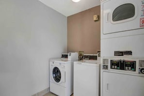 A laundry room with two front-loading washing machines and a dryer. - Cozy 1 Full Bed | Mini Fridge (San Jose CA)