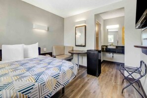 A hotel room with a bed, a desk, a chair, a small table, a mirror, and a kitchenette. - Cozy 1 Full Bed | Mini Fridge (San Jose CA)