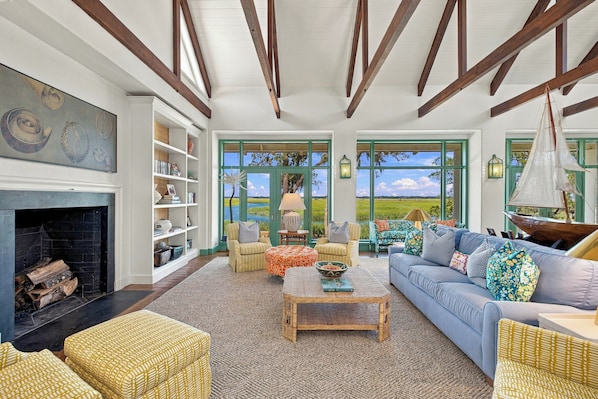 A spacious living room with a fireplace, a large window, and a view of the outdoors.