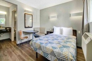 Een hotelkamer met een bed, bureau, stoel, spiegel en radiator.