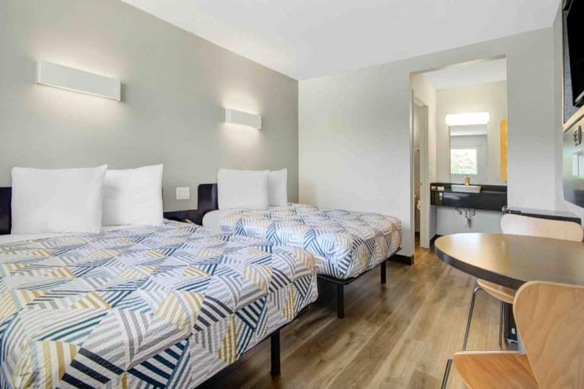 Ein Hotelzimmer mit zwei Betten, einer kleinen Küchenzeile und einem Essbereich.