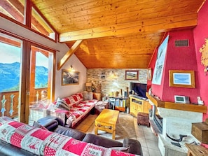 Een gezellige woonkamer met een open haard, een bank, een televisie en een stenen muur.