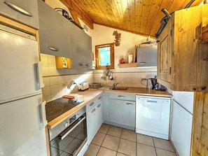 Een functionele keuken met een fornuis, oven, spoelbak en vaatwasser.