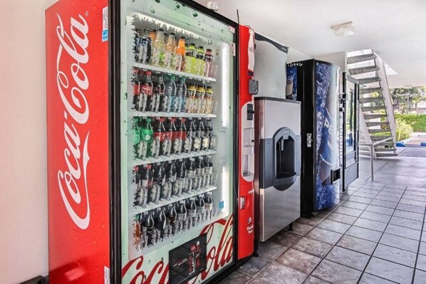 A vending machine area with a Coca-Cola branded machine and a refrigerator.