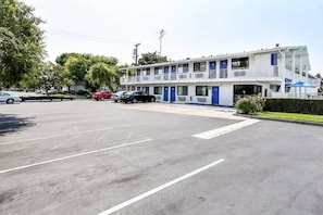 Un motel con un parcheggio, un edificio su più piani e alcune auto parcheggiate.