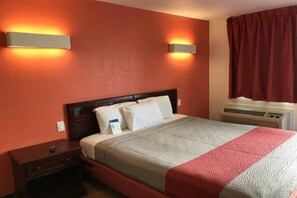 Habitació d'hotel amb un llit, taules de nit, un calefactor i una finestra amb cortines.