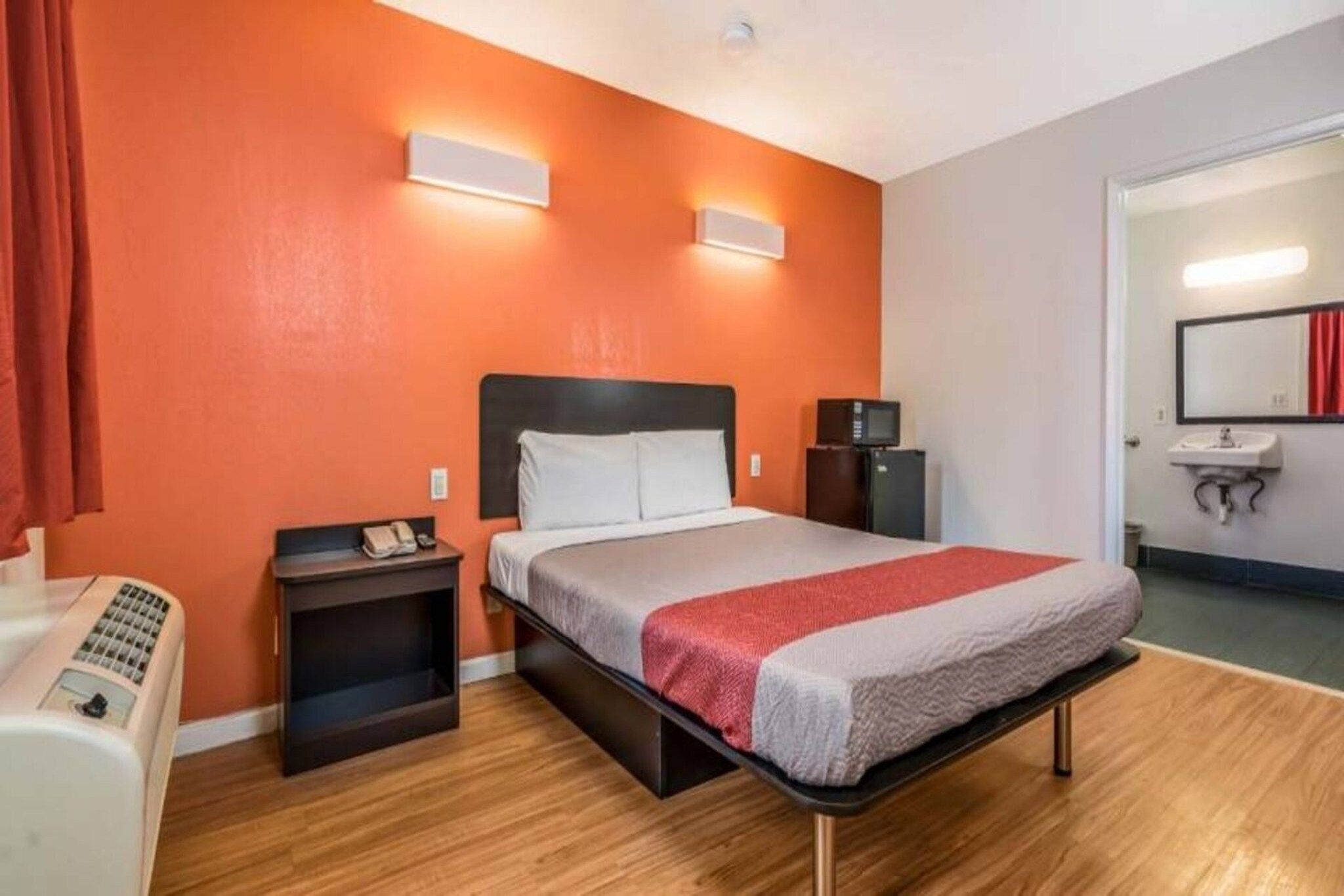 Une chambre d’hôtel comprenant un lit, des tables de chevet, un bureau avec un téléphone, un four à micro-ondes et un lavabo avec un miroir.