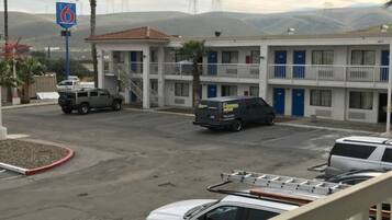 Un motel doté d’un parking, un bâtiment à étages et un paysage montagneux en arrière-plan.