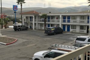 A motel with a parking lot, a building with multiple floors, and a mountainous backdrop.