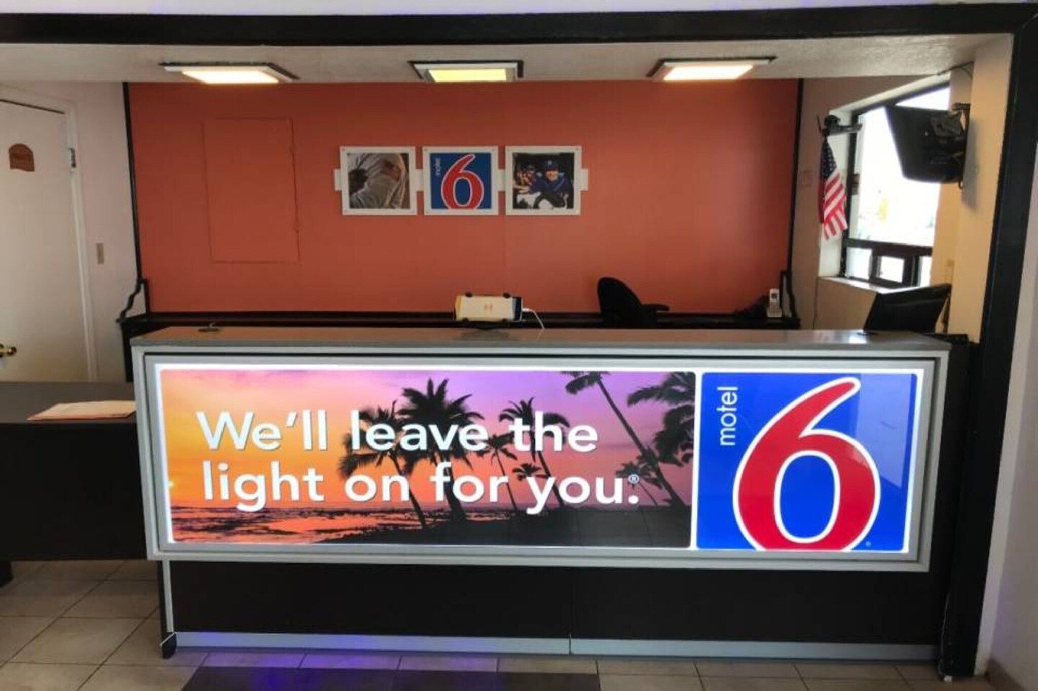 A hotel reception desk with a large sign stating 'We'll leave the light on for you.'