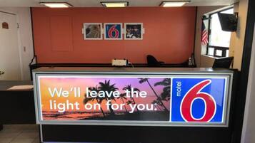A hotel reception desk with a large sign stating 'We'll leave the light on for you.'