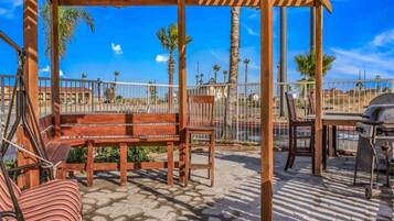An outdoor patio with a wooden pergola, seating area, and a barbecue grill.