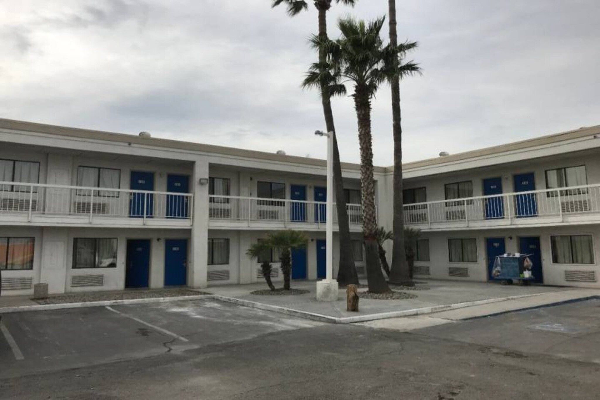 A multi-story motel with a parking lot in front.