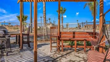 An outdoor patio with a wooden pergola, seating, and a grill.