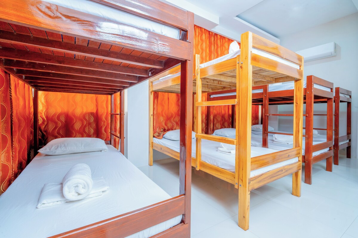 A room with bunk beds, a window with curtains, and a towel on the bed.