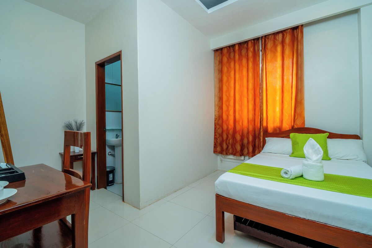 A hotel room with a bed, a desk, and a bathroom visible through an open door.