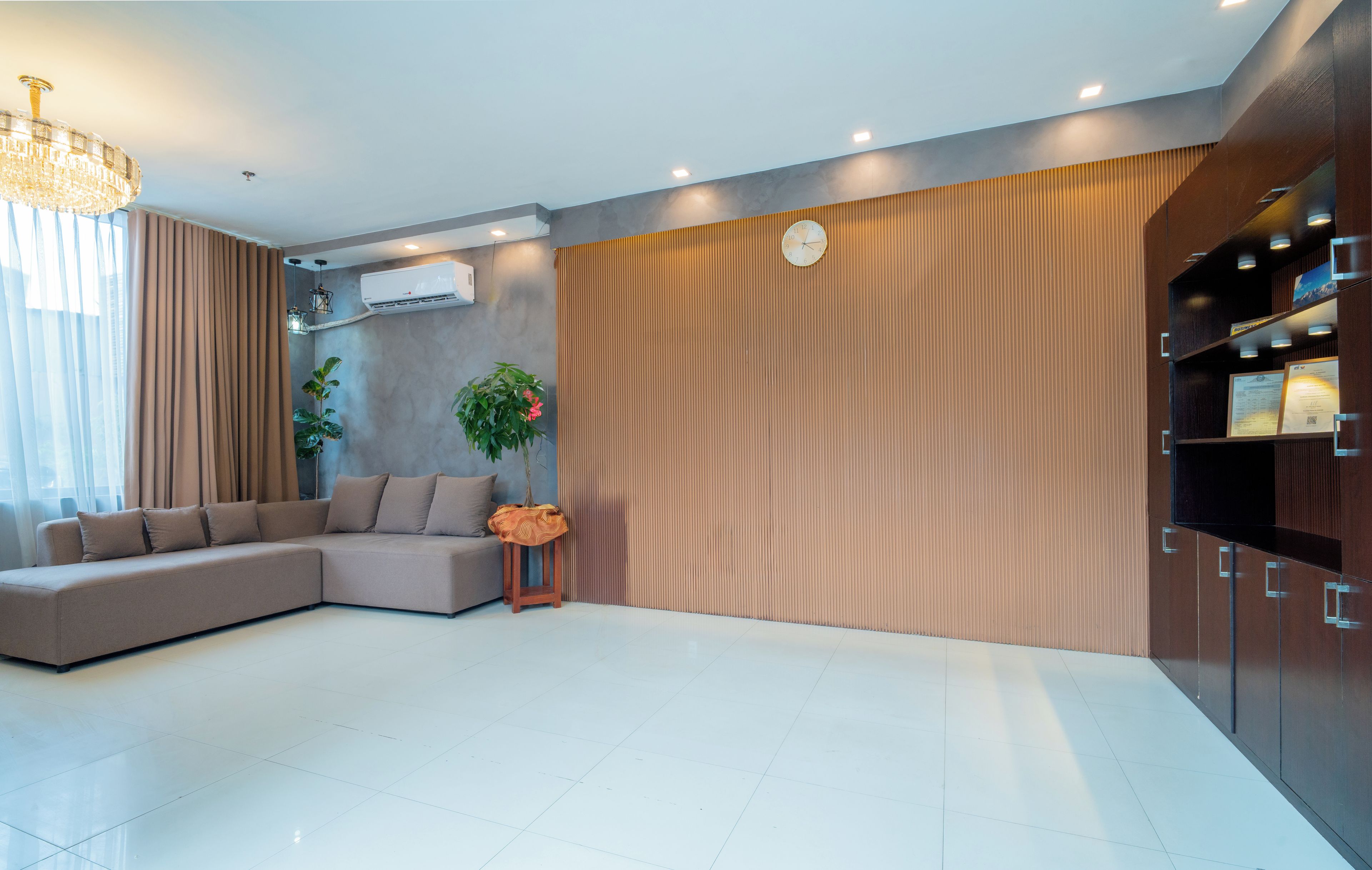 Una sala de estar moderna con un sof á seccional, una planta en maceta y un ventanal con cortinas.