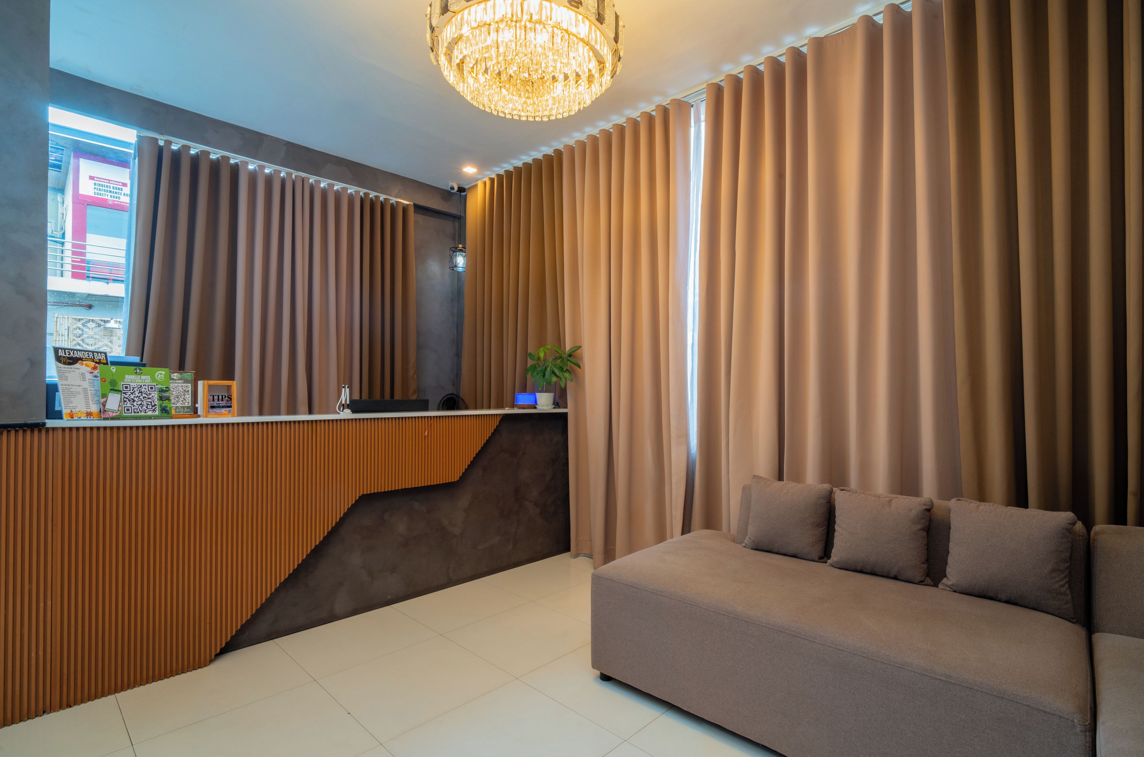 Una zona de recepción con mostrador de madera, un candelabro y un sofá.