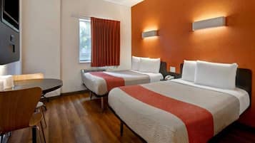 A hotel room with two beds, a desk, and a window with curtains.