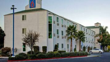 A 6-story hotel with a flat facade, multiple windows, and a parking lot with a single car.