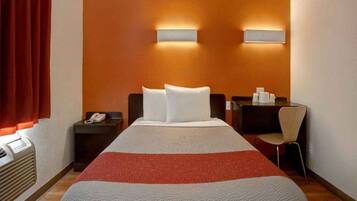Une chambre d’hôtel avec un lit, deux tables de chevet, une chaise et un bureau.