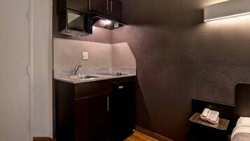 A compact kitchen with dark cabinetry, a stainless steel sink, and a microwave.