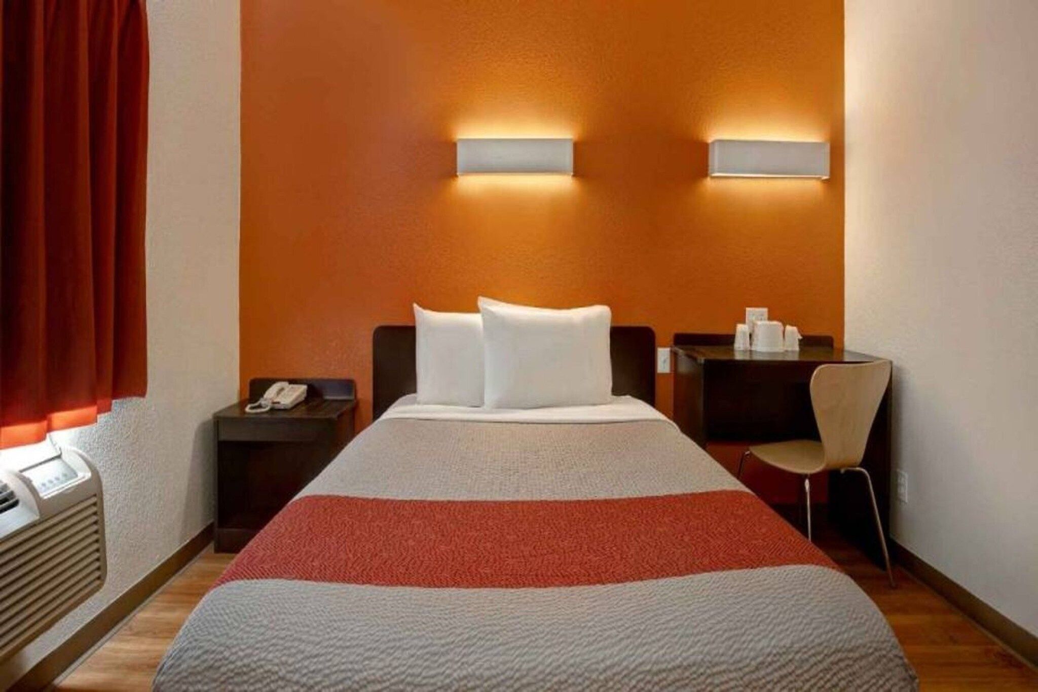 Una camera d'albergo con un letto, due comodini, una sedia e una scrivania.
