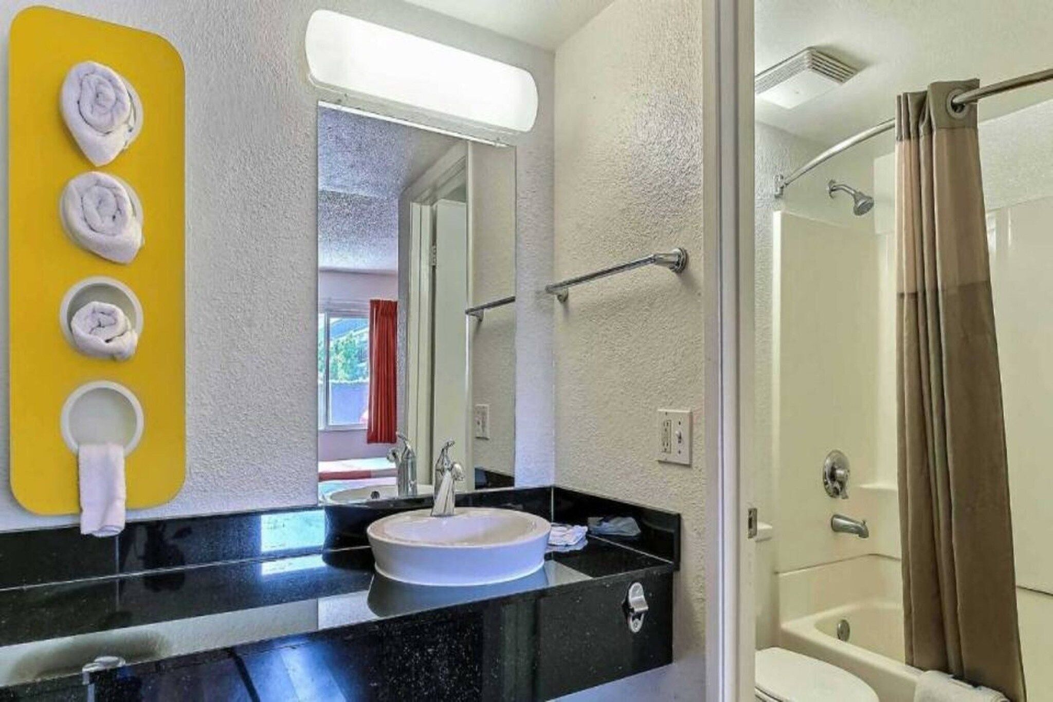 Casa de banho com lavatório, espelho e chuveiro.