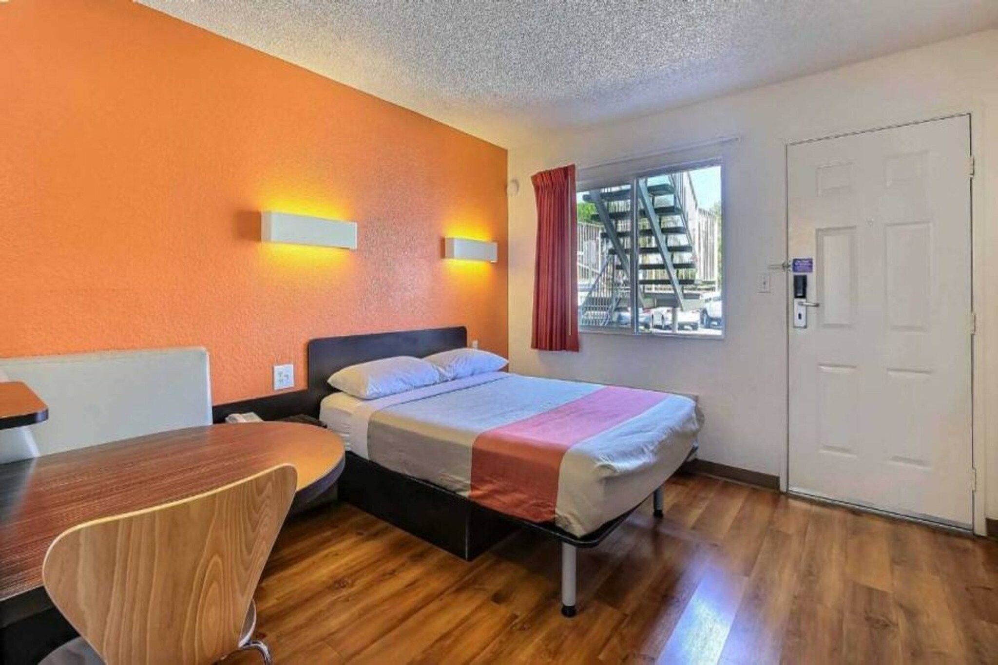 Una habitació d'hotel amb un llit, un escriptori i una cadira.