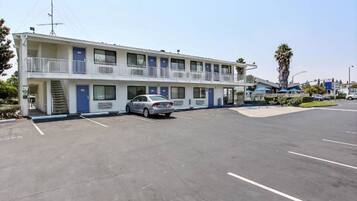 A motel with a two-story structure, a parking lot, and a single car parked in front.