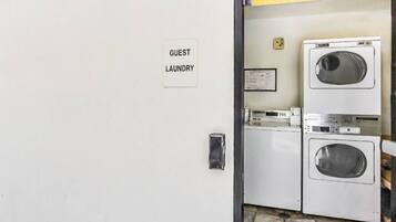 A laundry room with a sign indicating it's for guests, a washing machine, and a dryer.