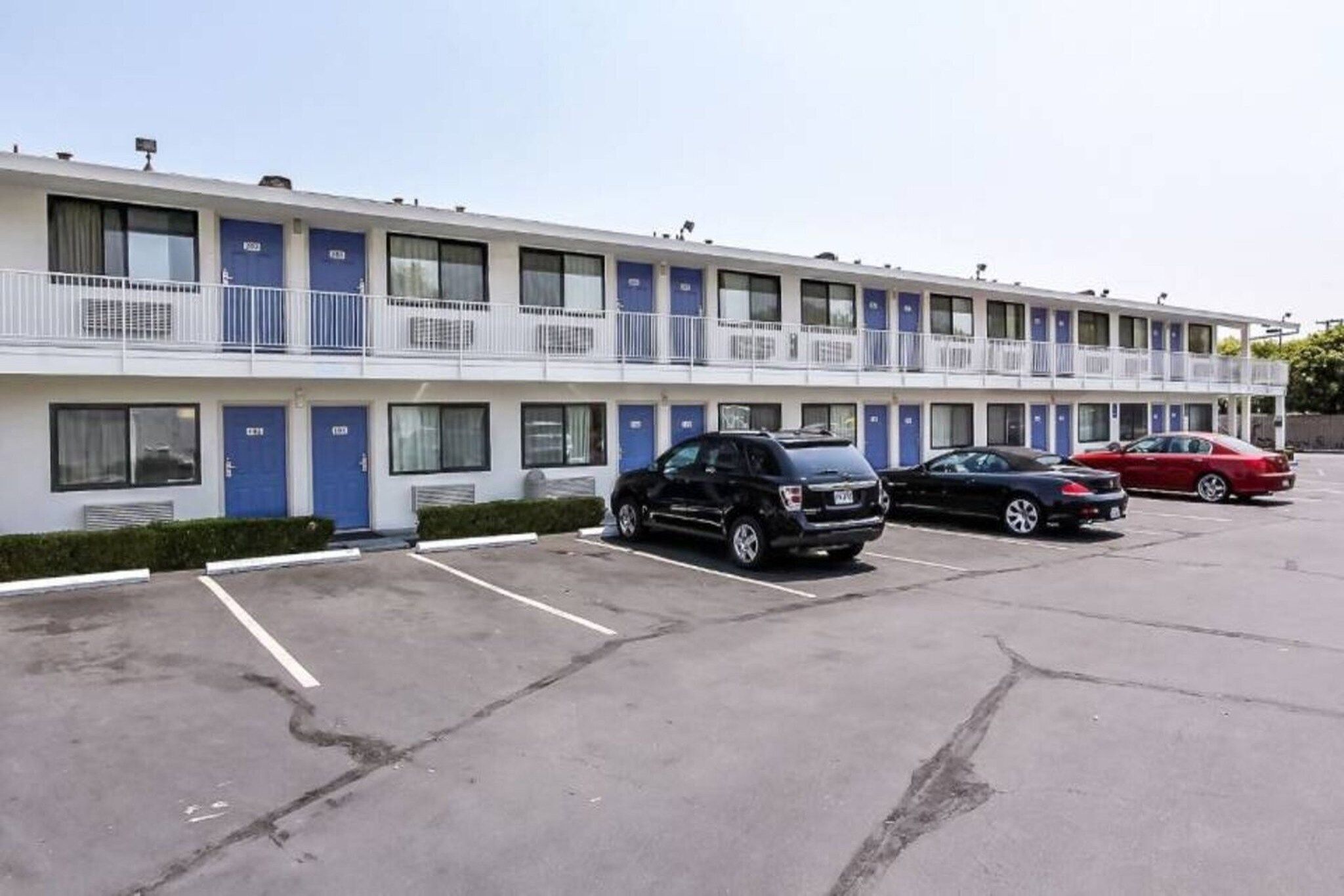 A motel with multiple rooms, a parking lot, and a few cars parked.