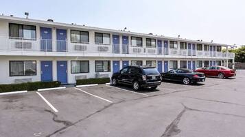 A motel with multiple rooms, a parking lot, and a few cars parked.