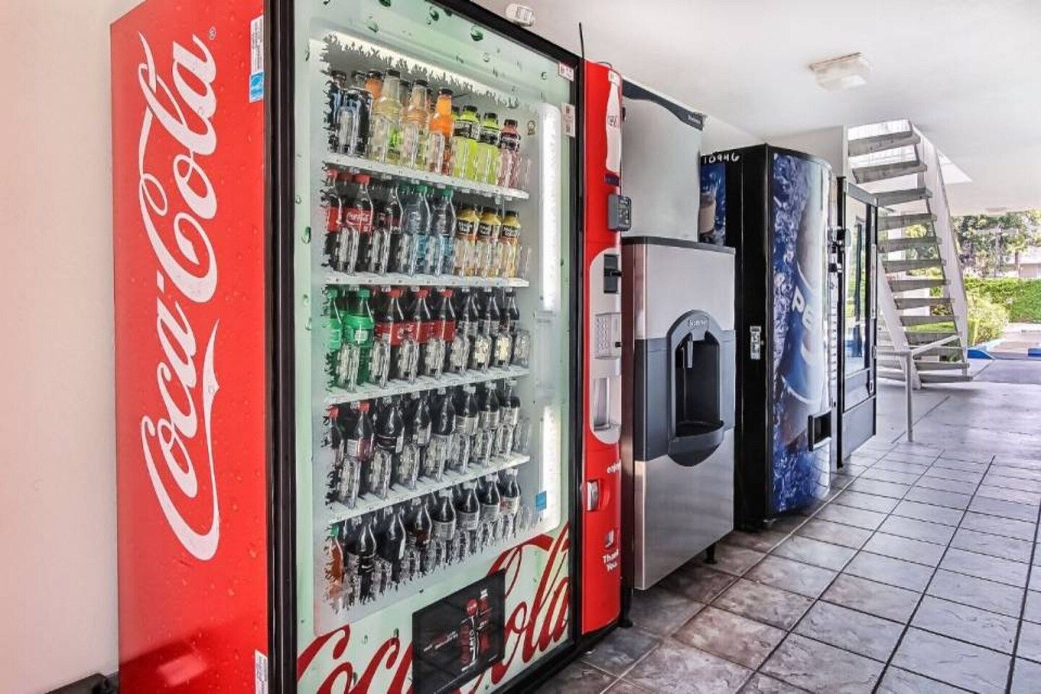 A vending machine area with a Coca-Cola branded machine and a refrigerator.