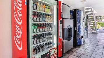 A vending machine area with a Coca-Cola branded machine and a refrigerator.