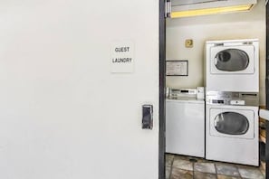 Een wasserette met een bordje dat aangeeft dat deze voor gasten is, een wasmachine en een droger.