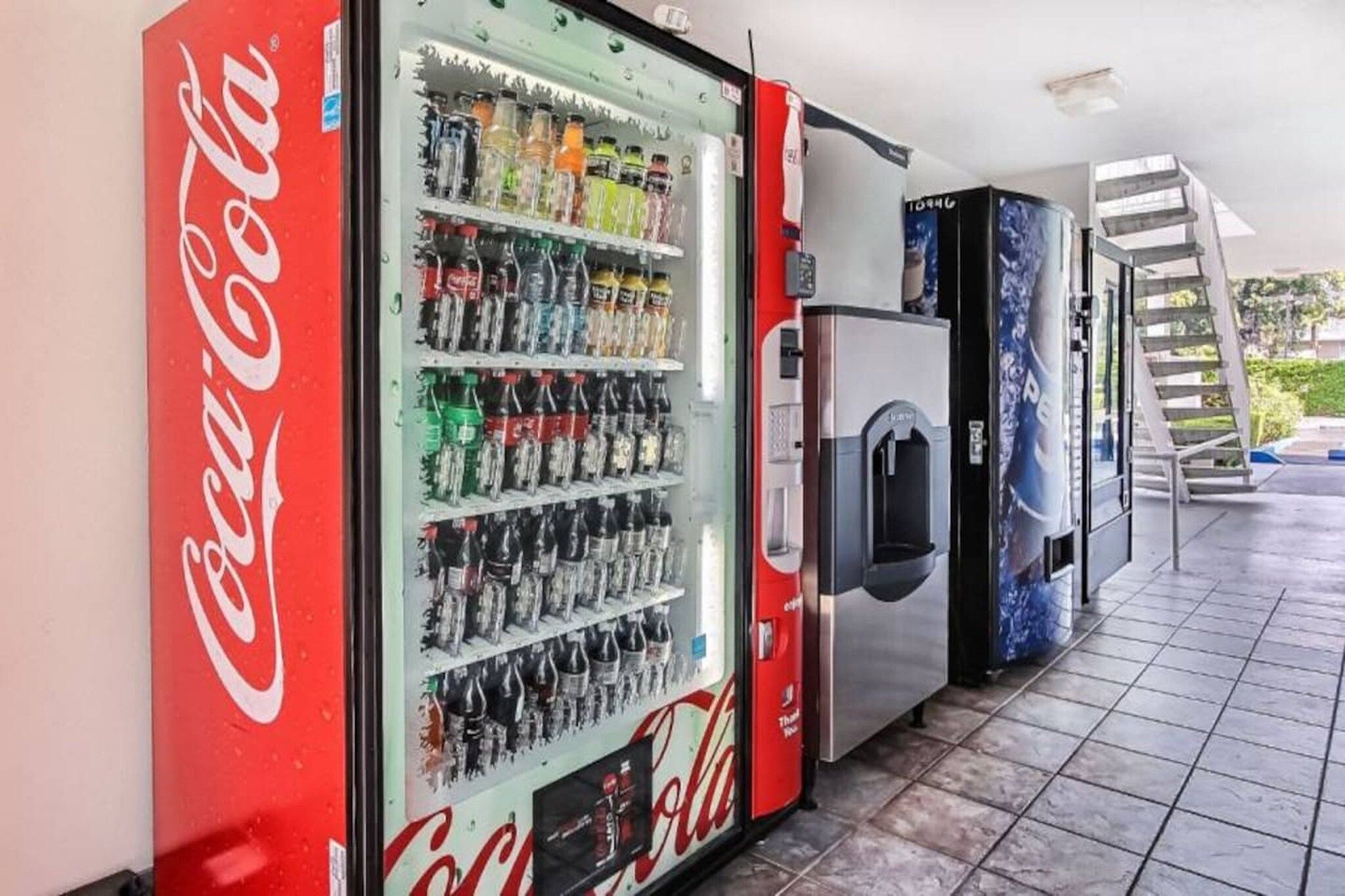 A vending machine area with a Coca-Cola branded machine and a refrigerator.