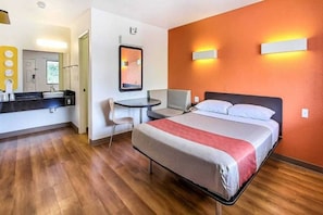 A hotel room with a bed, a desk, and a bathroom.