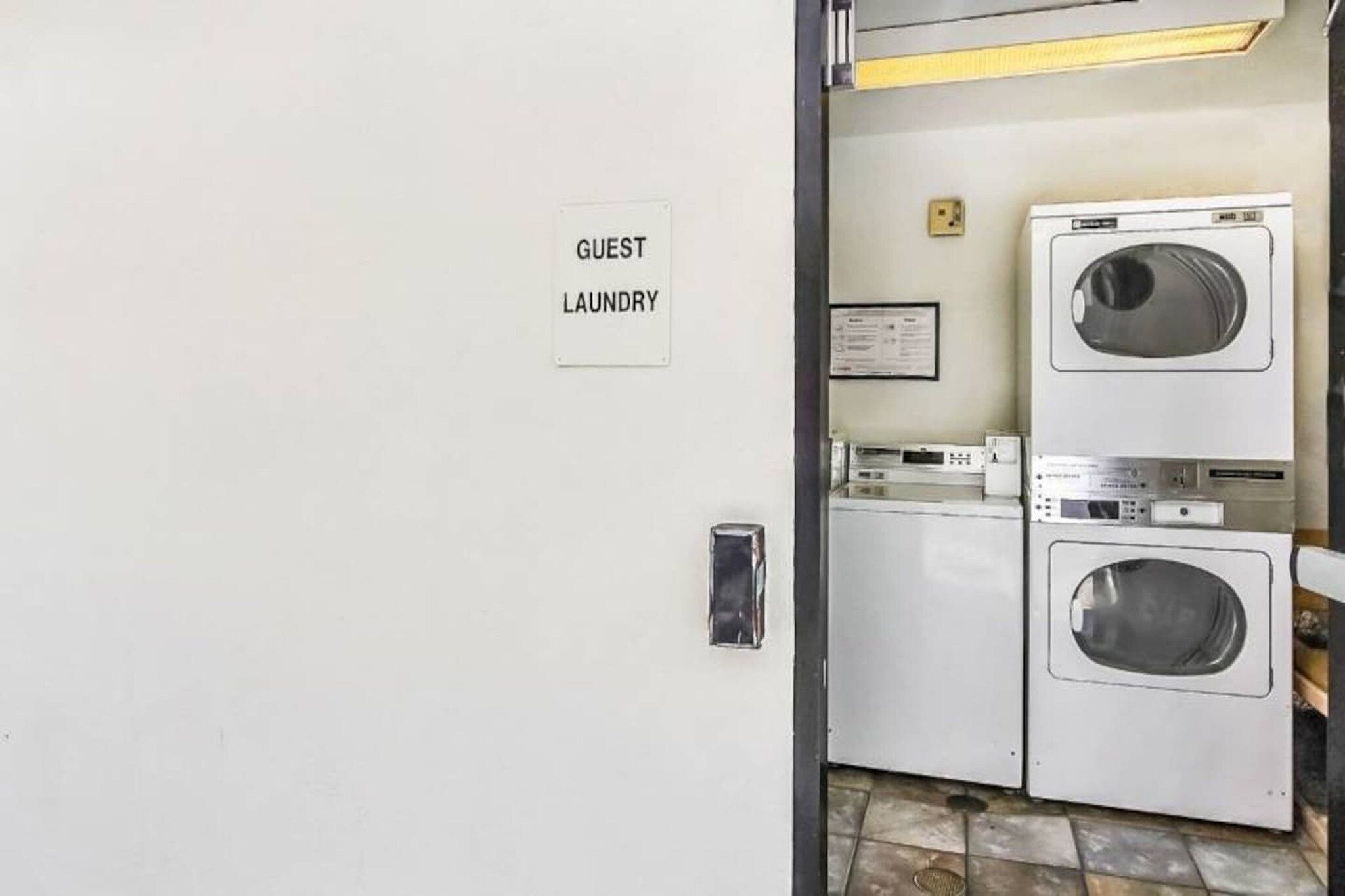 A guest laundry area with a sign, a washing machine, and a dryer.