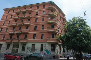 A multi-story building with balconies, a street in front, and a tree to the right. - Argonne Apartment - Corsica (Milano)