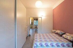 A bedroom with a bed, bedside tables, and a door leading to a bathroom. - Argonne Apartment - Corsica (Milano)