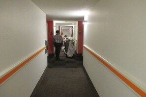 A hotel corridor with a carpeted floor, white walls, and orange trim. - 2 Full Beds | Deluxe, Micfridge (Sacramento CA)